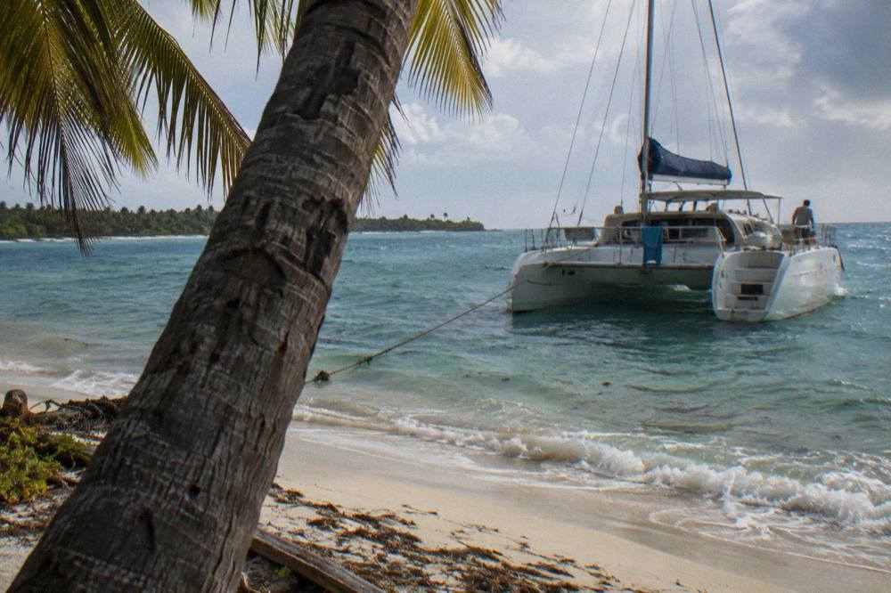 Catamaran anchored off a white sand beach with palm trees on Saona Island